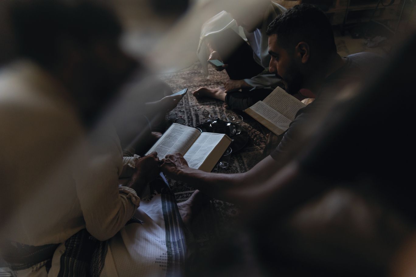 Vyrai ant grindų skaito Bibliją.